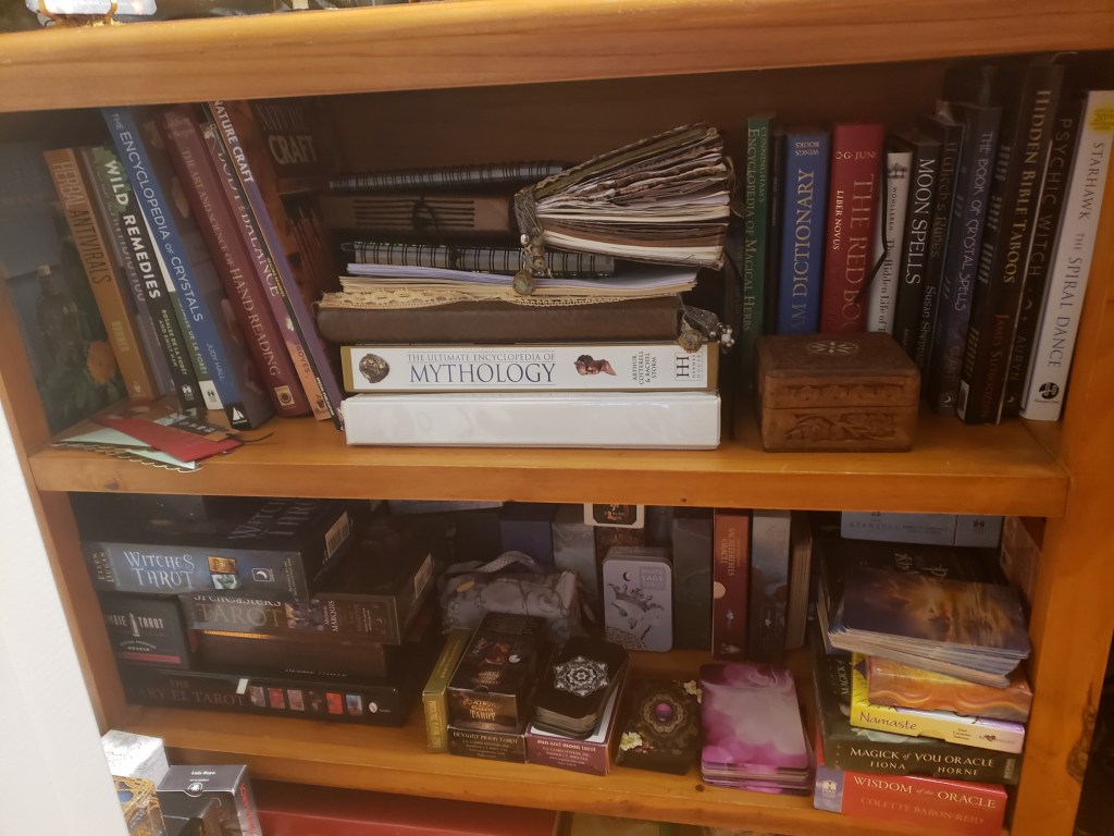 A bookshelf filled with witch books and tarot card decks